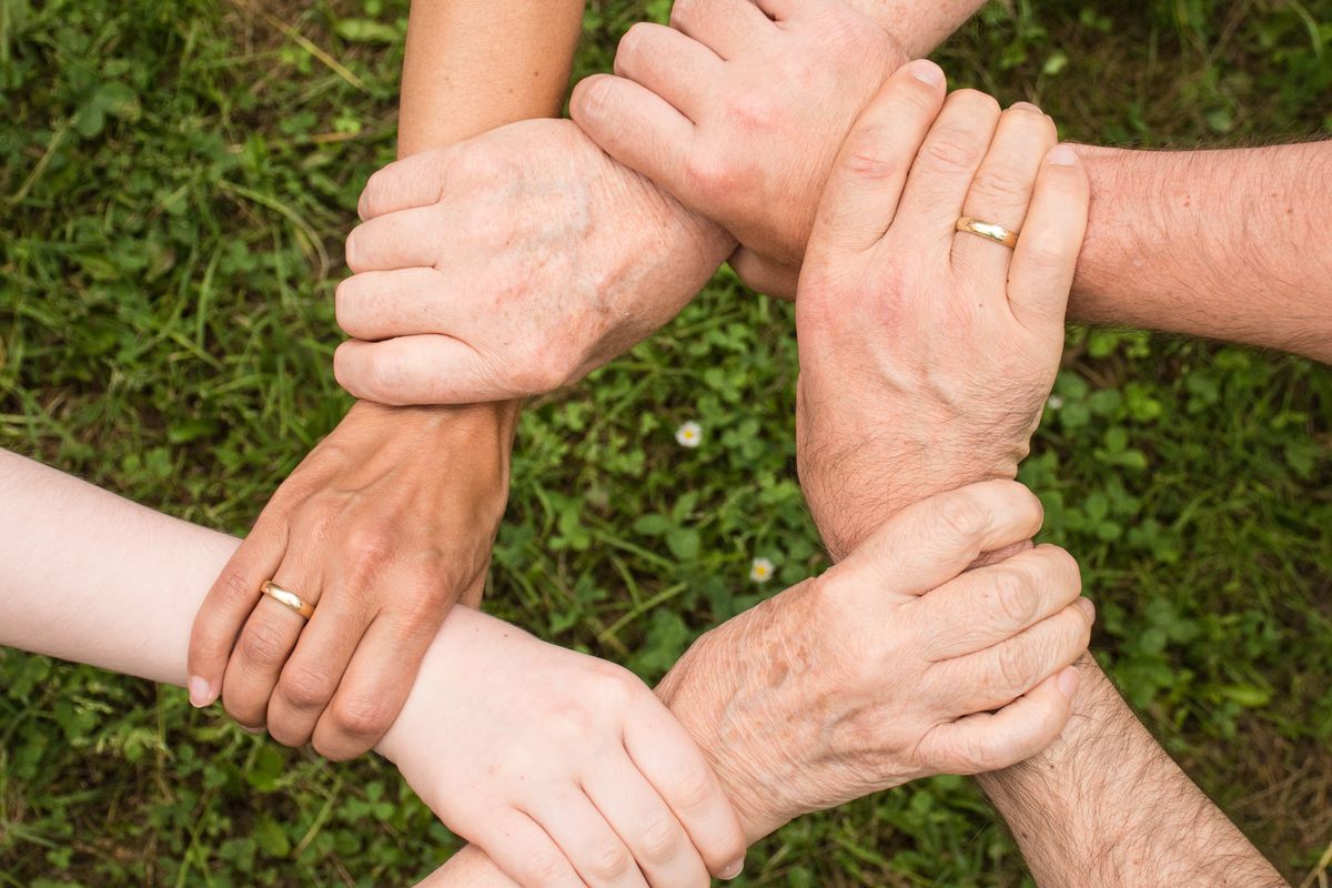 Gruppo di persone che uniscono le mani in cerchio, simbolo di cooperazione