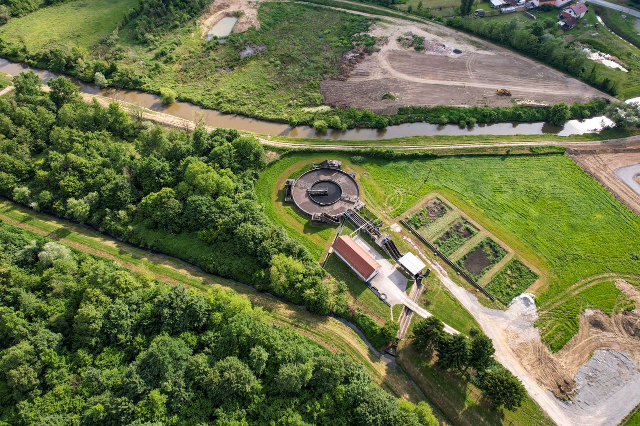 Vista aerea di un impianto di trattamento delle acque e dei rifiuti organici con vasche circolari, immagine simbolica del biodigestore pubblico che trasforma l'umido di 54 Comuni in biometano a Borgo San Dalmazzo, provincia di Cuneo