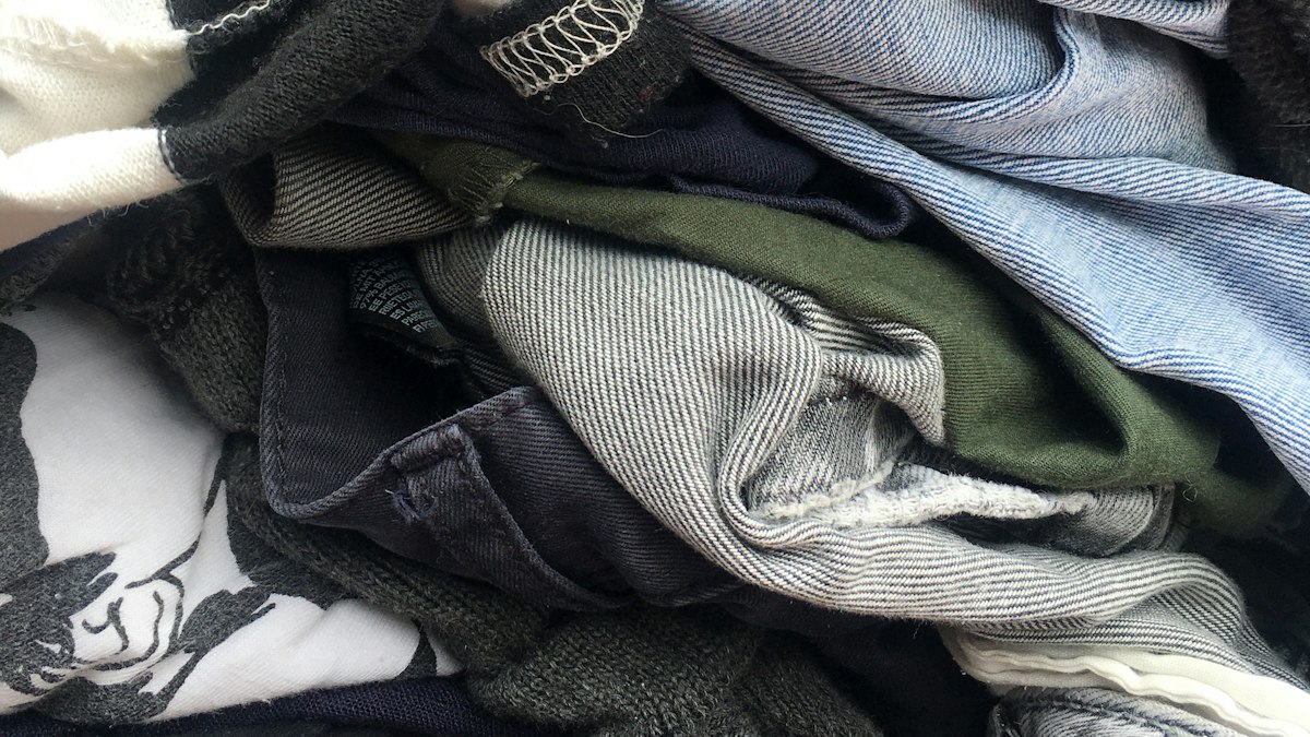 Mucchio di vestiti usati, jeans e magliette, immagine simbolica del Textile Hub di Prato che seleziona e ricicla i rifiuti tessili