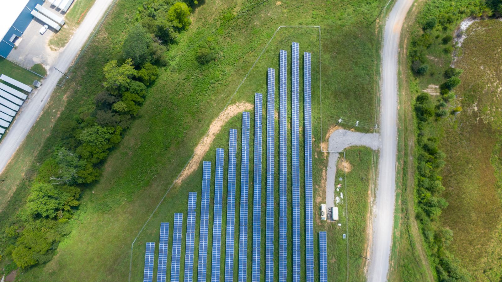 Vista aerea di un ampio campo fotovoltaico con pannelli solari disposti in file regolari