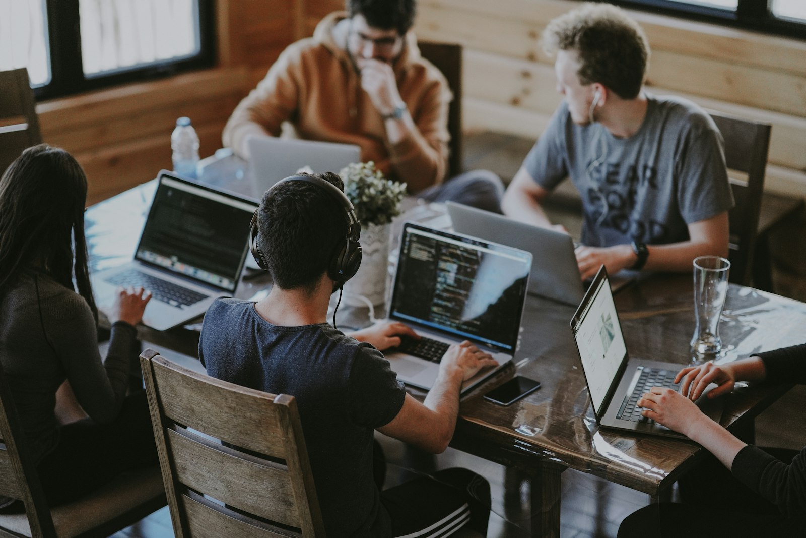 Gruppo di colleghi al lavoro su computer portatili attorno a un tavolo, immagine simbolica di una suite collaborativa per l'ufficio