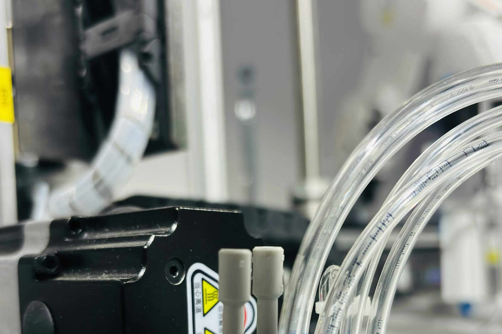 Dettaglio di un impianto industriale con tubi pneumatici trasparenti e componenti meccanici, immagine simbolica del monitoraggio IoT in fabbrica