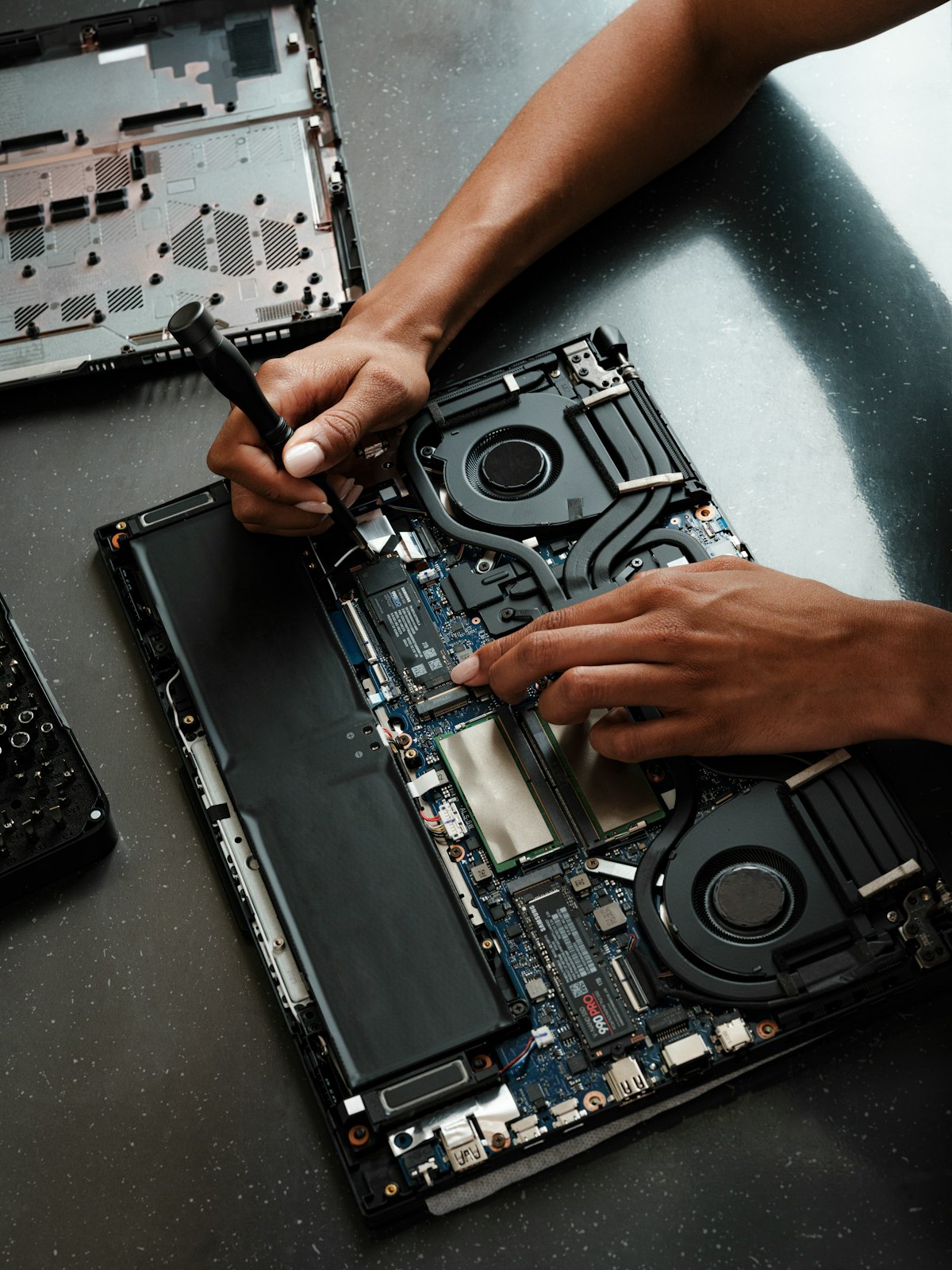 Tecnico che smonta un notebook con un cacciavite di precisione