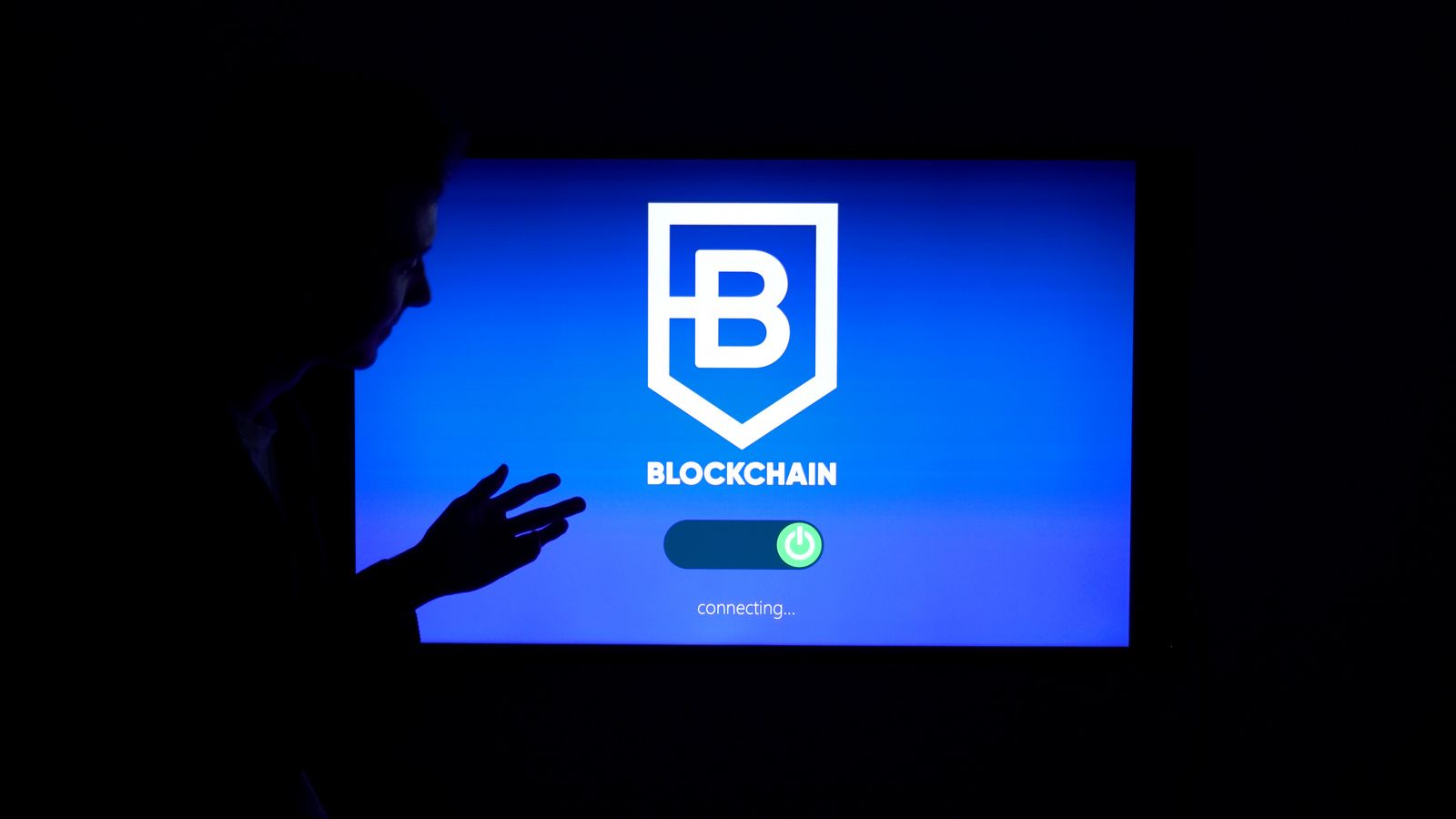 Persona davanti a uno schermo con dati e tecnologia blockchain