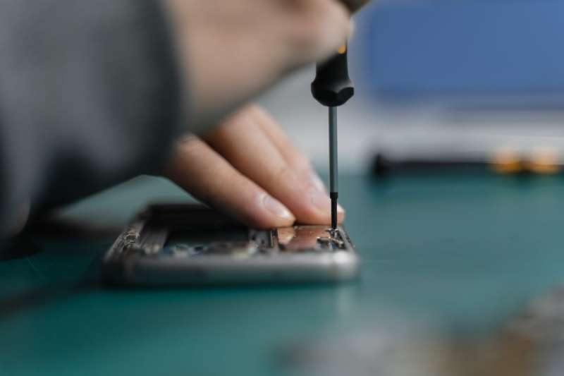 Mano che ripara un dispositivo elettronico con un cacciavite