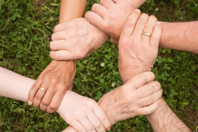 Gruppo di persone che uniscono le mani in cerchio, simbolo di cooperazione