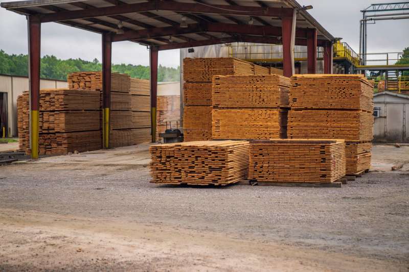 Cataste di assi di legno in un deposito all'aperto, simbolo dei materiali da costruzione recuperati dall'hub di Brooklyn
