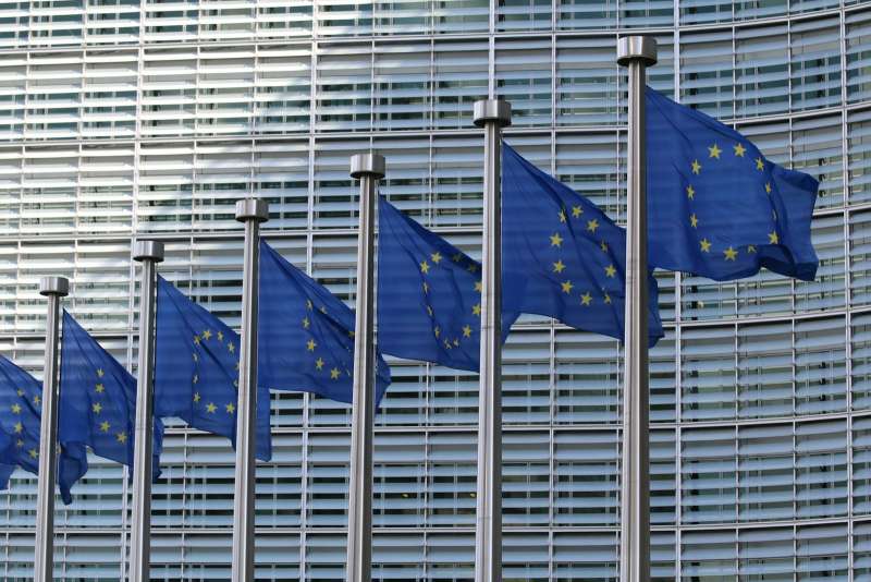 Fila di bandiere dell'Unione europea che sventolano davanti a un edificio, simbolo della sovranità digitale europea