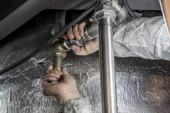 Tecnico assembla tubazioni industriali in acciaio durante l'installazione di un impianto tecnologico