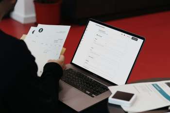 Persona alla scrivania con computer portatile e documenti cartacei, immagine simbolica della gestione amministrativa con un ERP