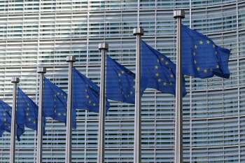Fila di bandiere dell'Unione europea che sventolano davanti a un edificio, simbolo della sovranità digitale europea