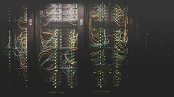 Armadi rack di un data center con cavi di rete e luci dei server accese, immagine simbolica della migrazione di Monaco di Baviera da VMware a Proxmox