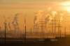 Linee elettriche e fumo industriale controluce al tramonto, simbolo di elettrificazione dei processi industriali
