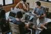Gruppo di colleghi al lavoro su computer portatili attorno a un tavolo, immagine simbolica di una suite collaborativa per l'ufficio